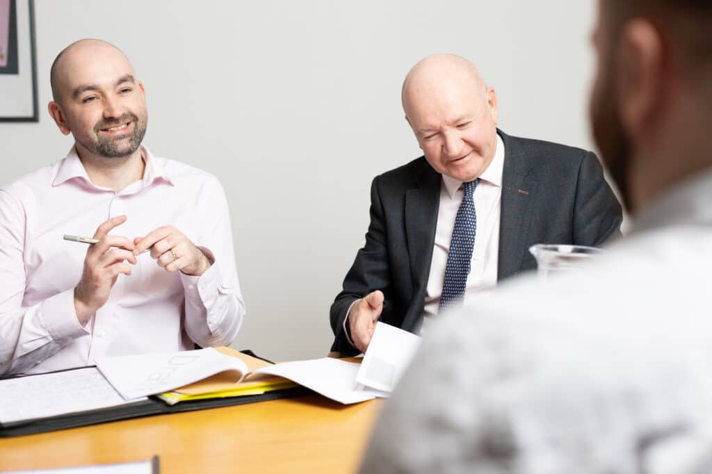 Two business professionals discussing documents at a meeting table.
