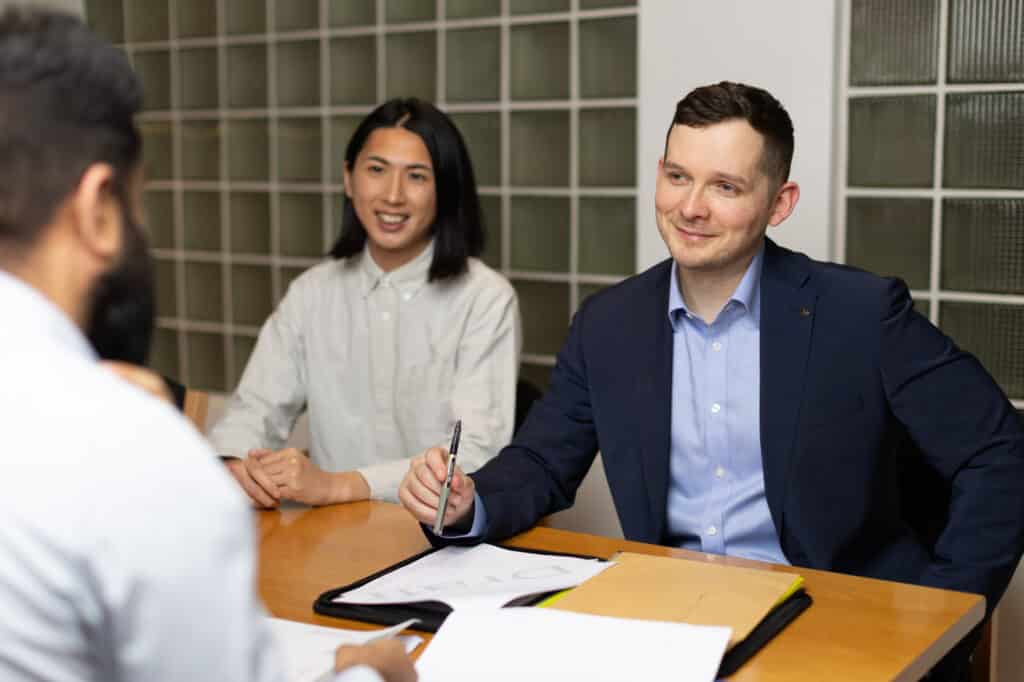 Business meeting with four people seated at a table, engaged in discussion.