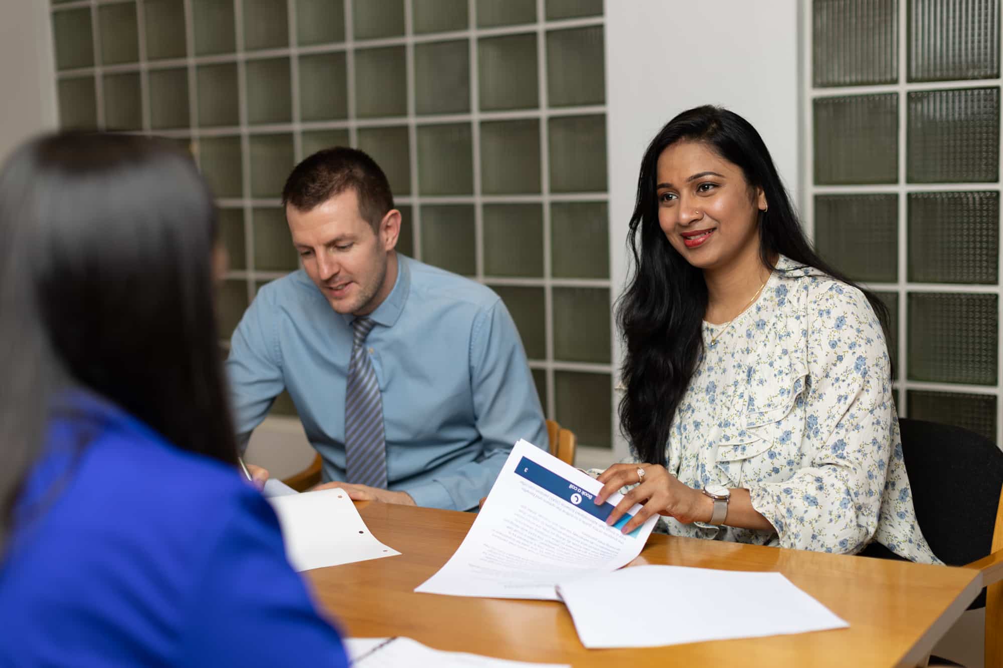 A group of people having a meeting at a table with documents.