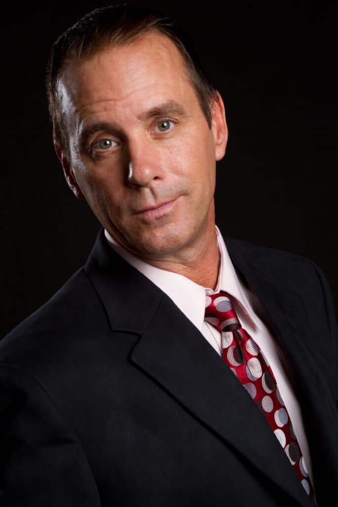 Businessman in suit and red tie against dark background.